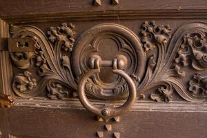 Podebrady, Czech. Old iron door handle on a iron door with carved flower detail photo