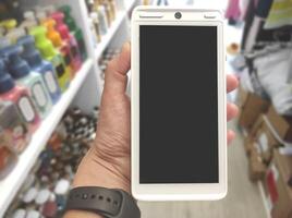 First-person photo, close-up of a hand holding a terminal for paying with a bank card in a store NFC payment POS terminal with a blank screen. Select a payment method for purchases in the store photo
