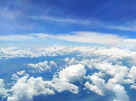 View from high above the blue sky with numerous cumulus clouds floating past the airplane window photo