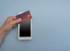 Contactless payment by debit or credit bank card. NFC payment POS terminal on a blue background with copy space. Select a payment method for purchases in the store photo