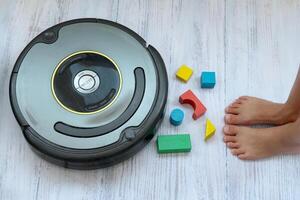 A robot vacuum glides across the light parquet floor, efficiently cleaning and vacuuming. The photo showcases the use of modern technology in a playful, family-oriented setting