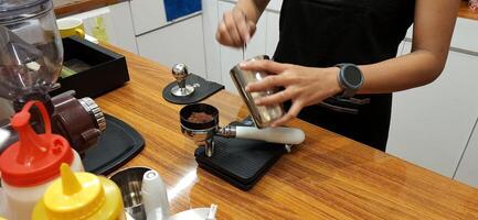 Close up Barista making coffee for customer in cafe. Woman working in coffee shop wearing an apron. Makassar, South Sulawesi, Indonesia - August 11 2024 photo