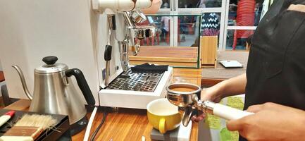 Close up Barista making coffee for customer in cafe. Woman working in coffee shop wearing an apron. Makassar, South Sulawesi, Indonesia - August 11 2024 photo