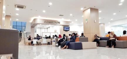 Atmosphere of patient queues to receive medical services at waiting area hospital. Makassar, South Sulawesi, Indonesia - August 12 2024 photo