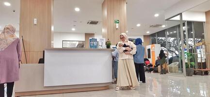 Atmosphere of patient queues to receive medical services at waiting area hospital. Makassar, South Sulawesi, Indonesia - August 12 2024 photo