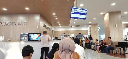Atmosphere of patient queues to receive medical services at waiting area hospital. Makassar, South Sulawesi, Indonesia - August 12 2024 photo