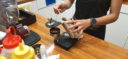 Close up Barista making coffee for customer in cafe. Woman working in coffee shop wearing an apron. Makassar, South Sulawesi, Indonesia - August 11 2024 photo