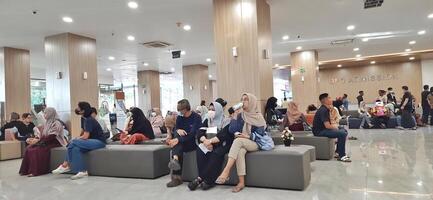 Atmosphere of patient queues to receive medical services at waiting area hospital. Makassar, South Sulawesi, Indonesia - August 12 2024 photo