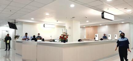 Atmosphere of patient queues to receive medical services at waiting area hospital. Makassar, South Sulawesi, Indonesia - August 12 2024 photo