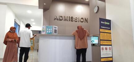 Atmosphere of patient queues to receive medical services at waiting area hospital. Makassar, South Sulawesi, Indonesia - August 12 2024 photo