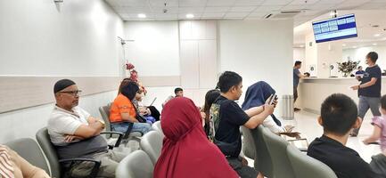 Atmosphere of patient queues to receive medical services at waiting area hospital. Makassar, South Sulawesi, Indonesia - August 12 2024 photo