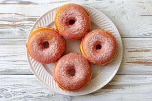 Top view of glazed donuts on white plate and wooden table. Sweets and pastries for backgrounds for confectioneries and cafes photo