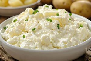Creamy potato salad garnished with chives in a white bowl. Classic side dish for summer photo