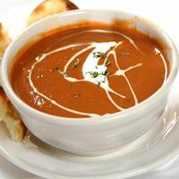 A Bowl of Delicious Tomato Soup. This Soup is Garnished with Sour Cream, Overhead view With Naan photo