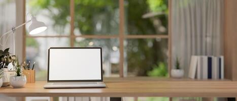 A laptop computer mockup on a wooden table in a contemporary, simple room. photo