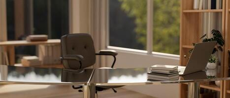 A modern office desk features a laptop, books, and decor plants in a contemporary room. photo