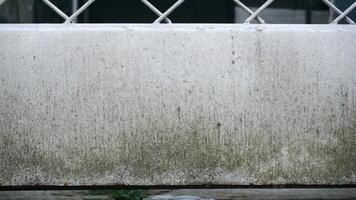 White concrete wall with grille and green grass. Dirty background texture. photo
