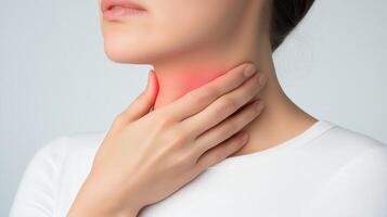 A close-up of a woman holding her throat, indicating pain or discomfort, with a soft background for a soothing effect. photo