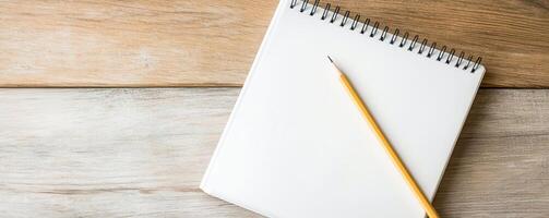 A blank notepad and pencil on a wooden table, perfect for brainstorming, sketching ideas, or writing notes. photo
