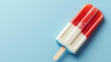 A vibrant popsicle with red, white, and blue layers resting on a light blue background, perfect for summer treats and fun. photo