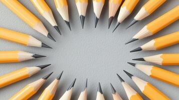 A circle of sharpened yellow pencils arranged on a grey background, ideal for educational and creative projects. photo
