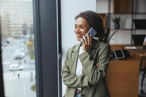 Whitecollar worker chatting on cell phone by window in office building photo