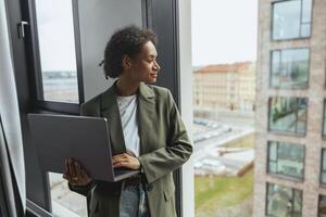 a woman is using a laptop computer while looking out of a window photo