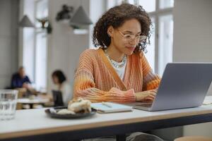 A woman is seated at a desk utilizing a laptop computer in a modern cafe photo