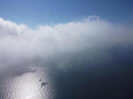 Aerial view. The drone flies over foggy and fluffy clouds. Blue sky sun and sea fog. Abstract aerial nature summer ocean sunset sea and sky background. Vacation, travel and holiday concept photo