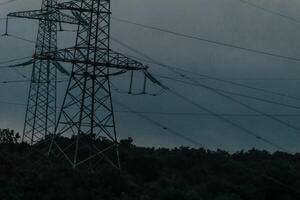 High voltage electric distribution network at sunset. Power transmission lines on supports with ceramic insulators and transformers at large electrical distribution substation photo
