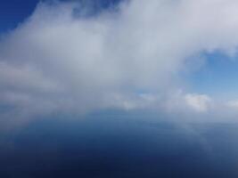 Aerial view. The drone flies over foggy and fluffy clouds. Blue sky sun and sea fog. Abstract aerial nature summer ocean sunset sea and sky background. Vacation, travel and holiday concept photo
