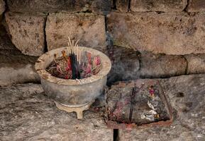 incense burner made of stone with a background of ancient piles of stones photo