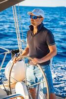 Young man captain stands at the helm and controls a sailboat during a journey by sea. High quality photo