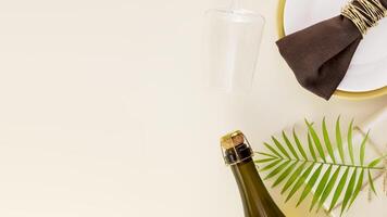 Gift with palm leaf, bottle of champagne and glass on a beige background photo