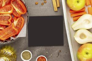 Empty black board with fresh vegetables and fruits on baking trays photo