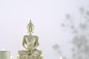 White Buddha statue with candles on a white background with copy space photo