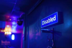 A bright blue sign labeled Disabled illuminates a wall, emphasizing accessibility in a low-light setting. photo