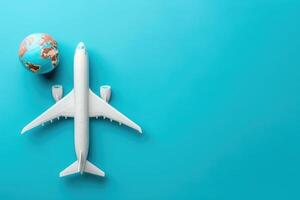 A sleek model airplane sits alongside a globe, symbolizing adventure and global travel against a bright turquoise background. photo