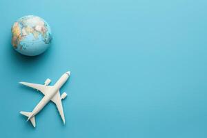 A model airplane rests next to a globe, symbolizing adventure and exploration against a clean blue background. photo