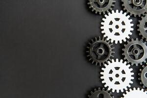 An arrangement of black and white gears on a solid black background highlights the theme of business process automation. photo