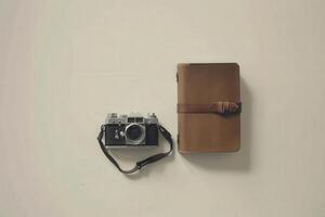 A vintage camera rests beside a well-worn travel journal, inviting memories and adventures on a neutral surface. photo