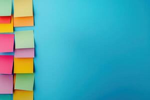 Brightly colored sticky notes are creatively positioned on a smooth blue surface, showcasing an organized yet playful aesthetic. photo