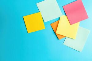 A collection of colorful sticky notes in various shapes and colors contrasts sharply against a bright blue backdrop, inviting creativity and organization. photo
