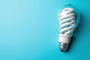 A compact fluorescent light bulb rests on a tranquil blue background, symbolizing energy efficiency and eco-friendly living. photo