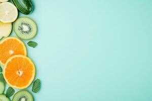 A vibrant assortment of citrus fruits, cucumber, and kiwi creatively displayed against a mint green background. photo