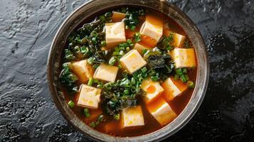 A bowl of miso soup with tofu, seaweed, and green onions. photo
