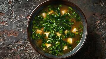 A bowl of miso soup with tofu and green onions photo