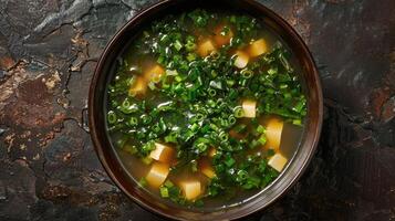 A bowl of miso soup with tofu and green onions photo