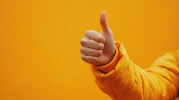 Hand Gesturing Thumbs Up in Yellow Jacket Against Yellow Background photo
