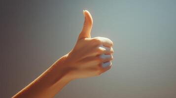 A Hand Giving a Thumbs-Up Gesture Against a Light Blue Background photo